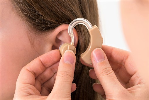 Doctor Inserting Hearing Aid In The Ear Of A Girl